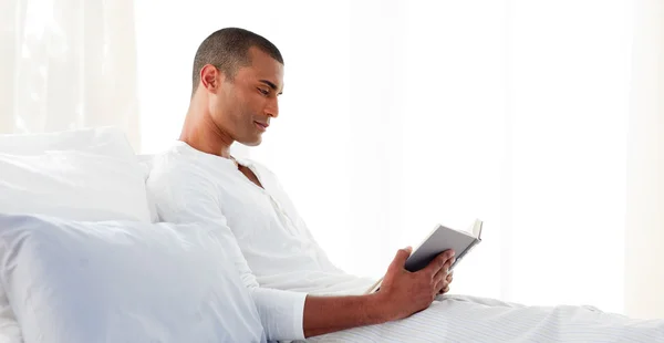 Концентрований чоловік читає лежачи на своєму ліжку — стокове фото
