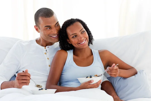 Cheerful couple having breakfast on their bed — Stock Photo, Image