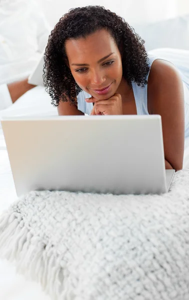 Sorrindo mulher usando um laptop em sua cama — Fotografia de Stock