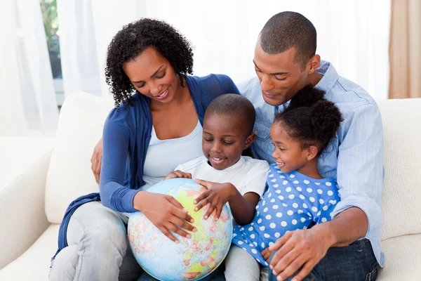 Familia feliz sosteniendo un globo terrestre — Foto de Stock