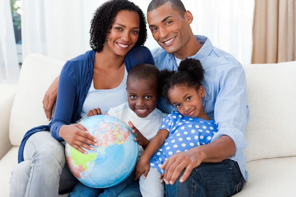Família afro-americana segurando um globo terrestre — Fotografia de Stock