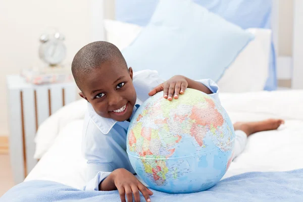 Jongen op zoek naar een globe terwijl glimlachen in de camera — Stockfoto