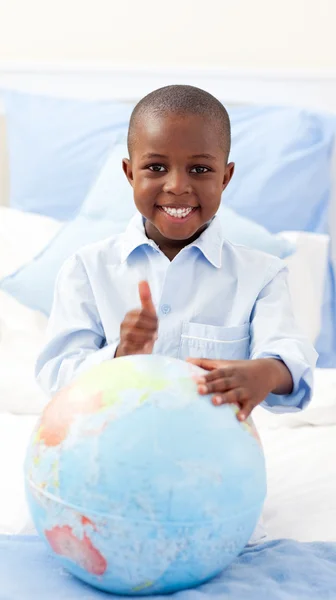 Niño sonriente sosteniendo un globo terrestre — Foto de Stock
