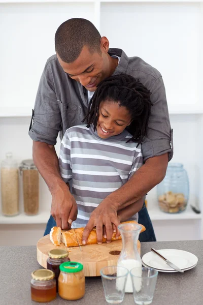 Счастливый отец режет хлеб со своим сыном — стоковое фото