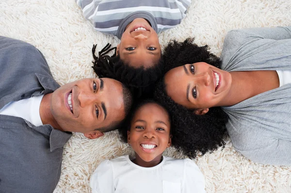 Família afro-americana no chão com cabeças juntas — Fotografia de Stock