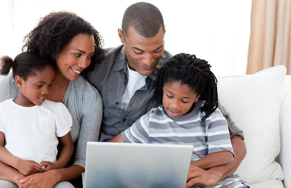 Família afro-americana usando um laptop no sofá — Fotografia de Stock