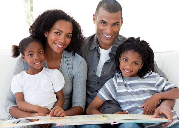 Porträt einer afroamerikanischen Familie, die im Wohnzimmer ein Buch liest — Stockfoto