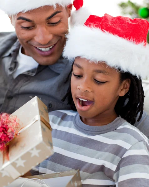 Retrato de um pai e filho afro-americano abrindo um Natal — Fotografia de Stock