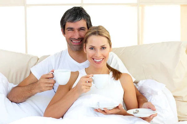 Casal afetuoso beber café deitado na cama — Fotografia de Stock