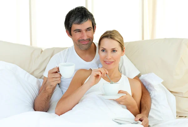 Casal feliz beber café deitado na cama — Fotografia de Stock