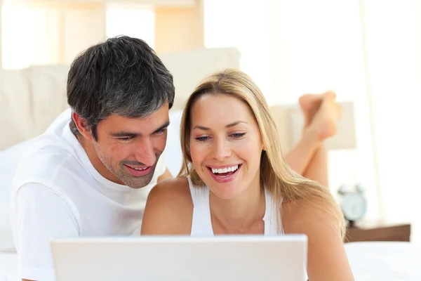 Close-up of lovers using a laptop lying on bed — Stock Photo, Image