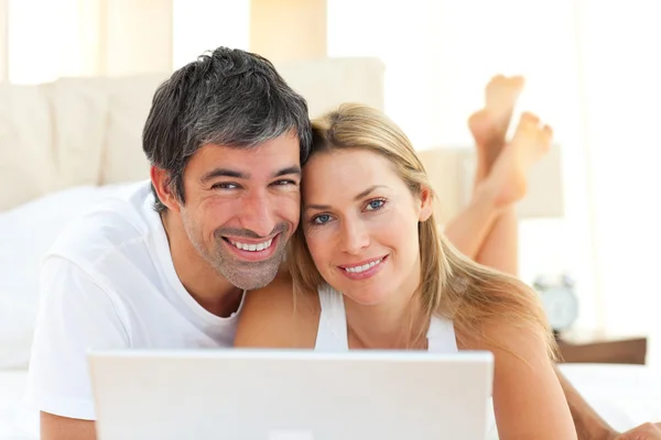 Verliebtes Paar mit Laptop im Bett liegend — Stockfoto