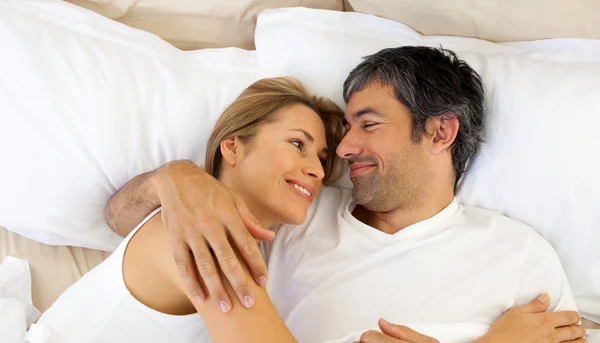 Ласковая пара, обнимающая лежащую в постели — стоковое фото
