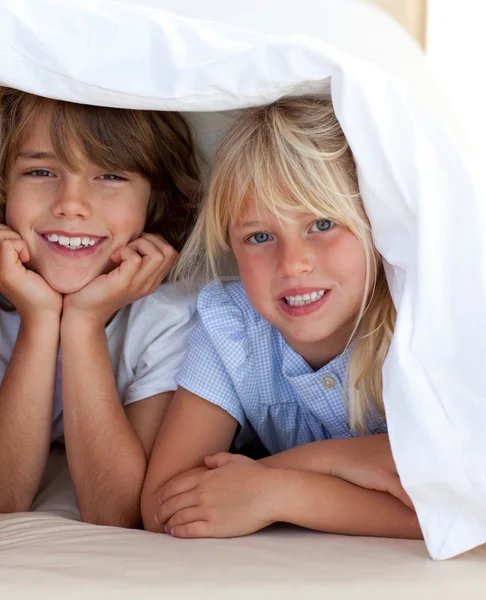 Lächelnde Geschwister spielen Undercover — Stockfoto