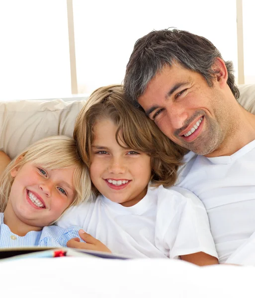 Glimlachend vader en zijn kinderen lezen van boek — Stockfoto