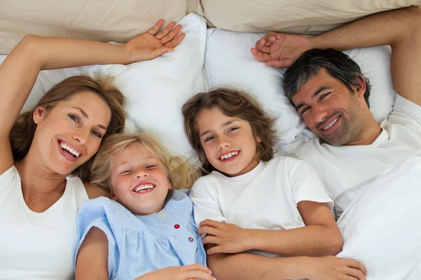 Famiglia sorridente si diverte in camera da letto — Foto Stock