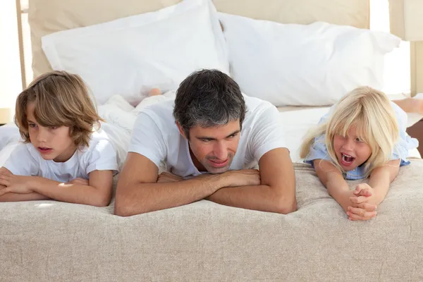 Отец и его дети разговаривают лежа на кровати — стоковое фото