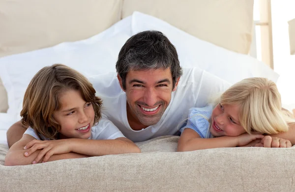Sonriente padre hablando con sus hijos acostados en la cama — Foto de Stock