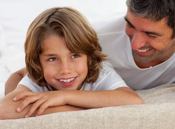 Cute little boy having fun with his father lying on bed — Stock Photo, Image