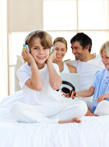 Gelukkig weinig jongen luisteren muziek zittend op bed — Stockfoto