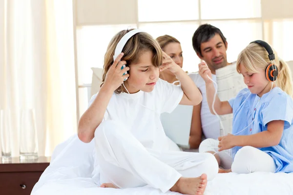 Frères et sœurs joyeux écoutant de la musique avec écouteurs — Photo