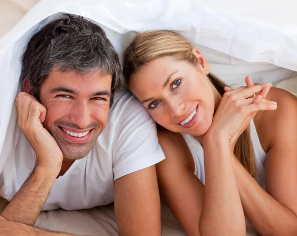 Влюбленная пара веселится лежа на кровати — стоковое фото