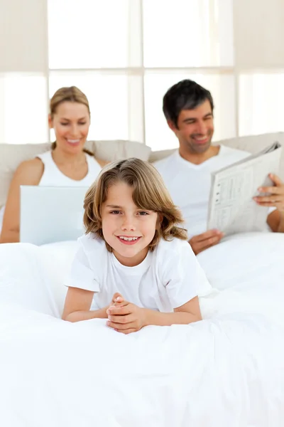 Gelukkige jongen met zijn ouders ontspannen in de achtergrond — Stockfoto
