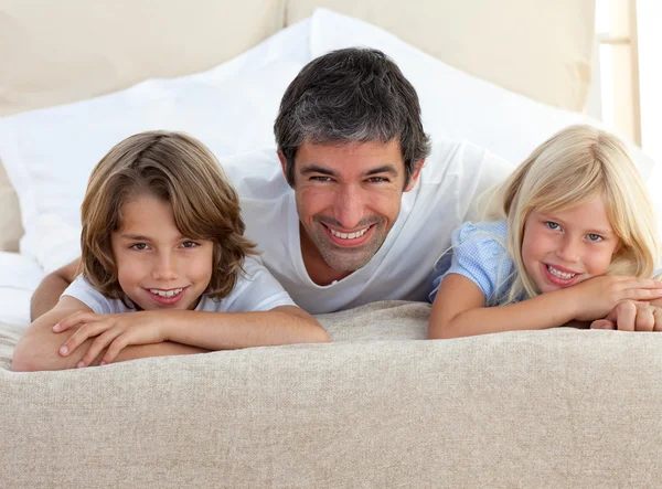 Заботливый отец и его дети лежат на кровати — стоковое фото