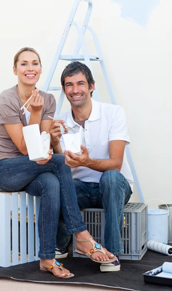 Smiling couple eating while decorating a room — Stock Photo, Image