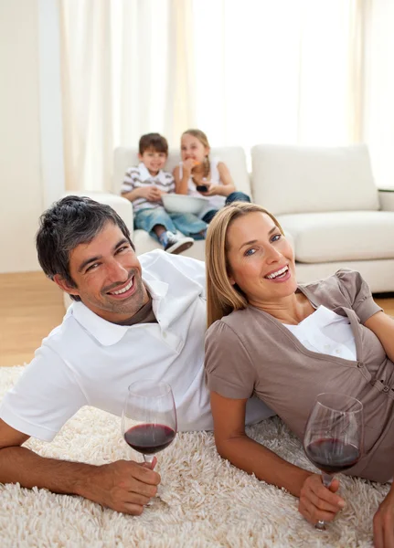 Smiling lovers drinking wine lying on the floor — Stock Photo, Image