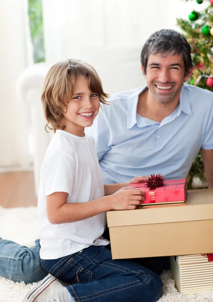 Père souriant et son fils ouvrant cadeaux de Noël — Photo