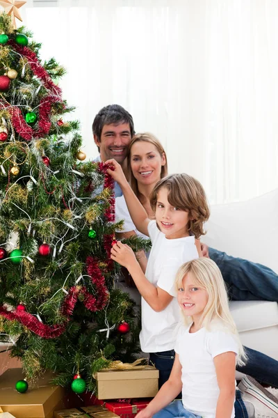 Föräldrar och deras barn dekorera en julgran — Stockfoto