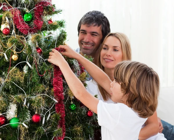 Niño colgando decoraciones de Navidad con sus padres —  Fotos de Stock
