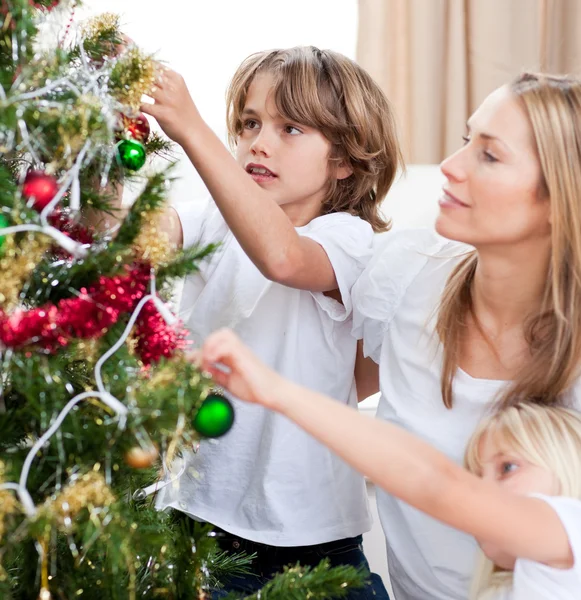 Children hanging Christmas decorations with their mother — Stock Photo, Image