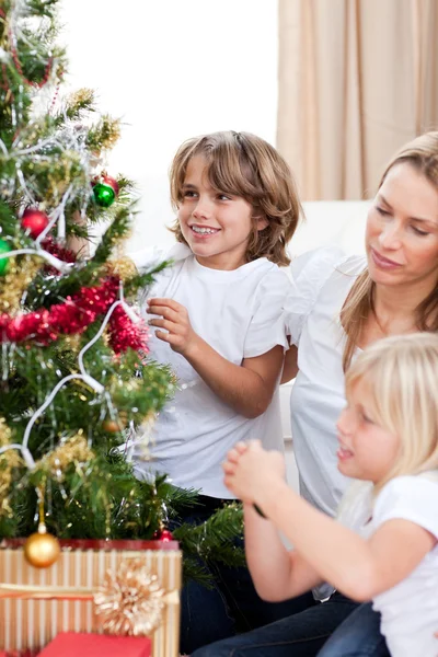 Glückliche Mutter und ihre Kinder hängen Weihnachtsdekoration auf — Stockfoto