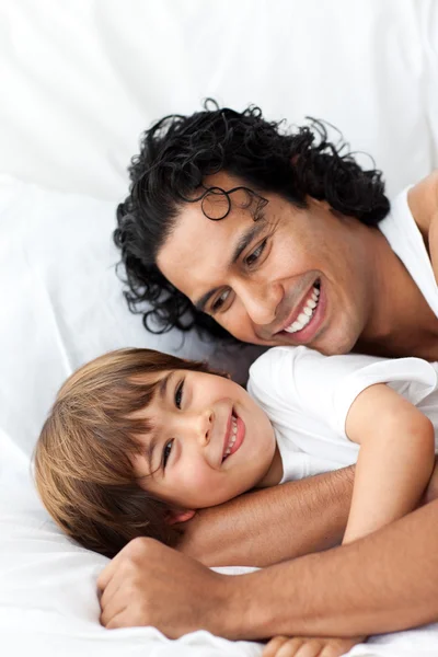 Szczęśliwy ojciec i jego mały chłopiec, leżąc na łóżku — Zdjęcie stockowe
