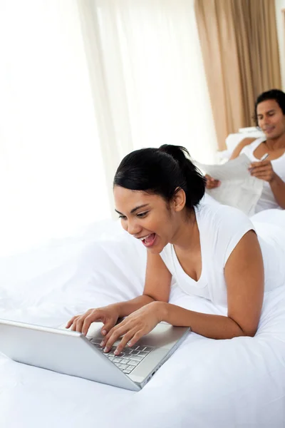 Bir kadın yatakta yatarken bir dizüstü bilgisayar kullanarak — Stok fotoğraf