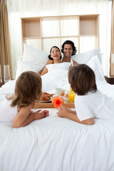Happy family having breakfast lying on the bed — Stock Photo, Image