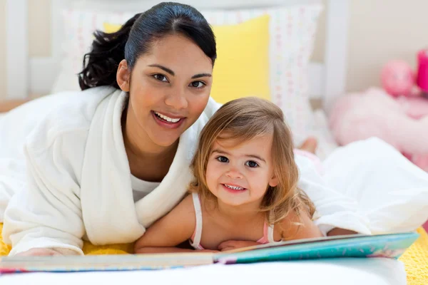 Портрет улыбающейся матери и ее дочери, читающей вместе — стоковое фото