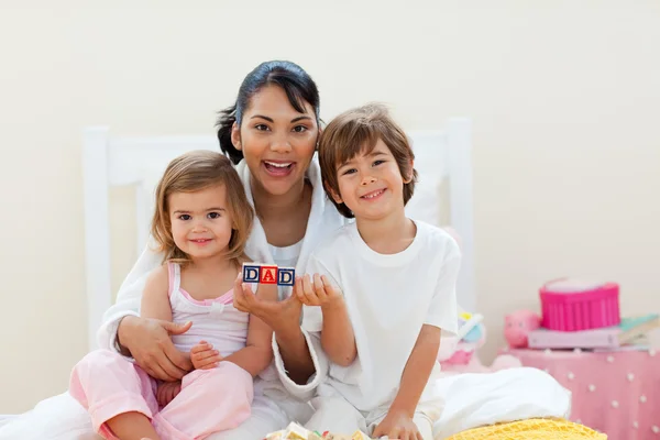 Attractive mother and her children playing with letters blocks — Stock Photo, Image