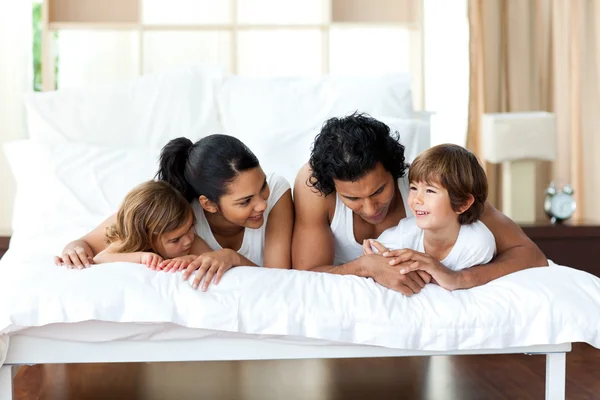 Retrato de una familia sonriente acostada en la cama — Foto de Stock