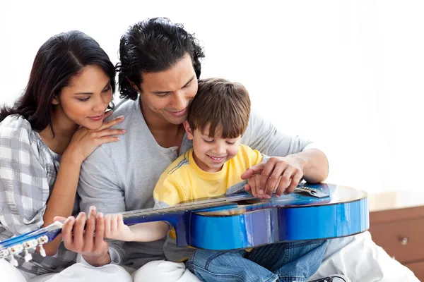 Szczęśliwy chłopiec gra na gitarze z rodzicami — Zdjęcie stockowe