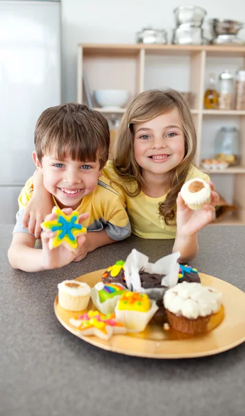 Adorable siblings showing their cookies — Stock Photo, Image
