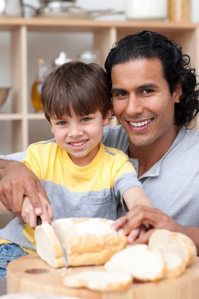 Lächelnder Vater hilft seinem Sohn beim Brotschneiden — Stockfoto