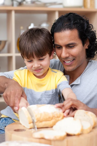 Aantrekkelijke vader helpen zijn zoon wat brood gesneden — Stockfoto