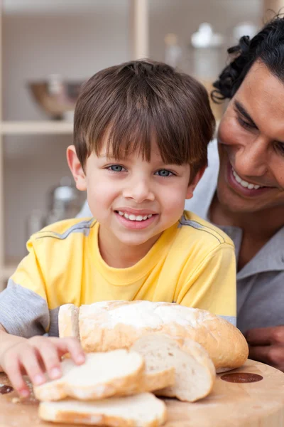 Smiling child eating bread with his father — Stock Photo, Image