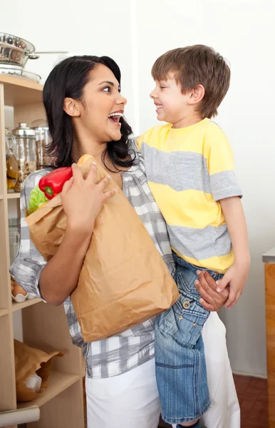 Schattige kleine jongen uitpakken kruidenier zak met zijn moeder — Stockfoto