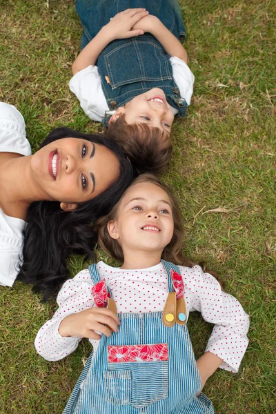 Mutlu anne ve çocukları çim üzerinde yalan — Stok fotoğraf