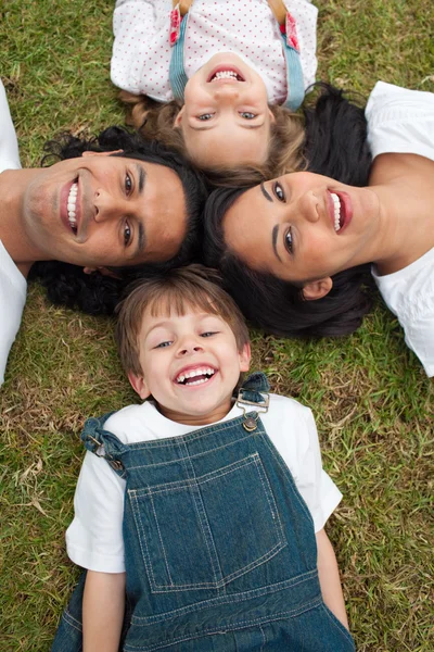 Little boy lying in a circle with his family in a park — Stock Photo, Image
