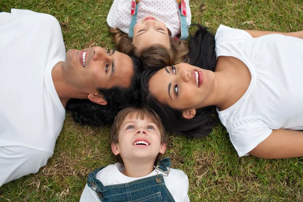 Vrolijke familie liggen in een cirkel op het gras — Stockfoto